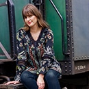 The model is wearing a colorful patterned blouse