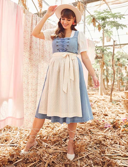 Two models pose in the same dirndl. One model wears a beige apron, the other model a dark blue apron