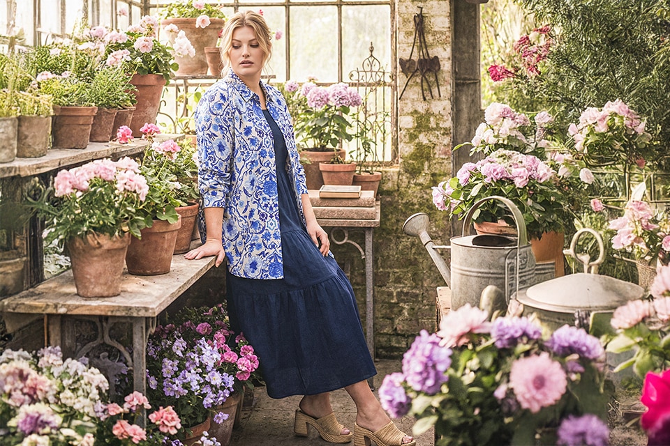 The model is wearing a blue and white blouse and a navy blue dress.