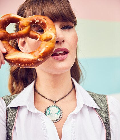 Close-up of brown-haired woman looking through pretzel 