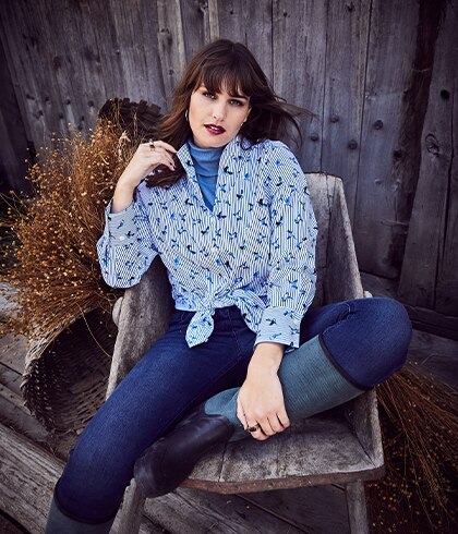 Woman with blue blouse and blue jeans posing on a chair 