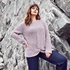 Woman in a pink sweater standing in front of a rock face
