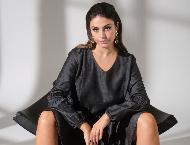 Woman in black dress sits on a chair