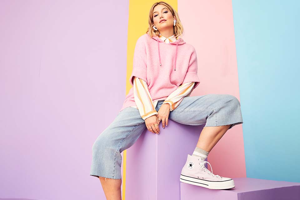 The model is wearing a pink tank top and jeans.