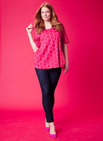 Brand Model posing in a pink shirt in front of a pink wall  