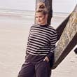 The model poses on the beach and wears a striped shirst 