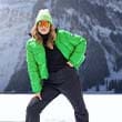 The model poses in the snow wearing a green jacket