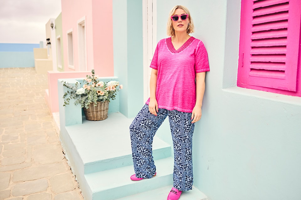 The model wears a pink shirt with patterned pants 